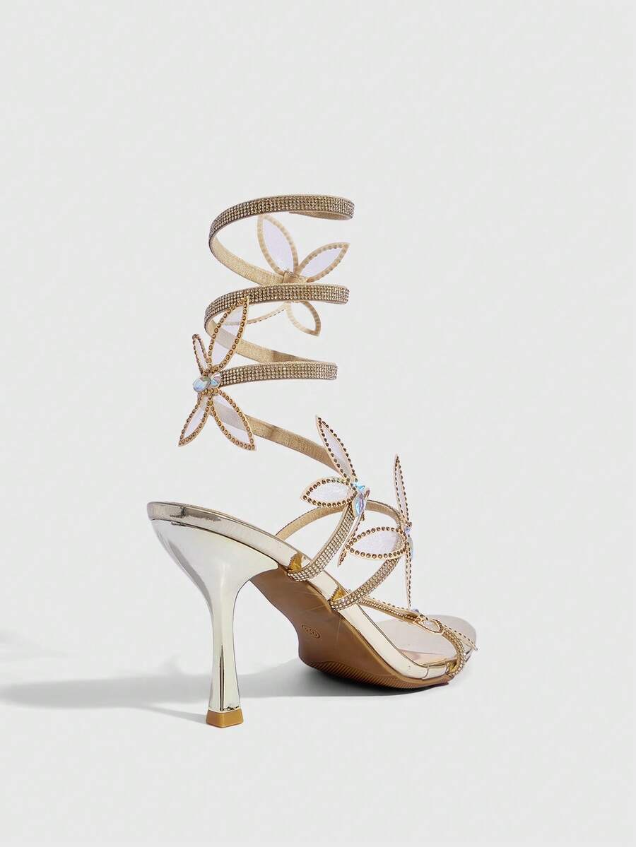 Gold stiletto high heel sandals with sparkling rhinestone bow accents and winding ankle straps for women
