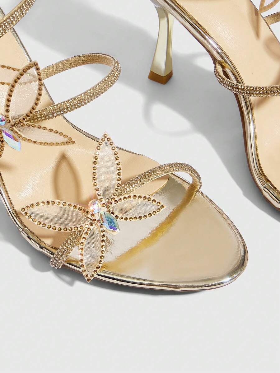 Gold stiletto high heel sandals with sparkling rhinestone bow accents and winding ankle straps for women