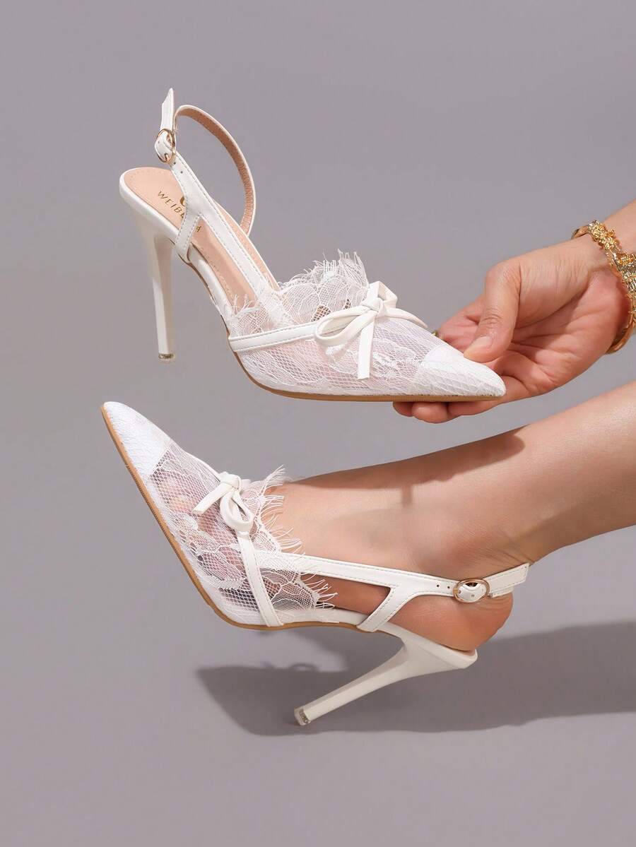 White pointed toe high heel stiletto sandals featuring lace patchwork, fringe trim, and an oversized bowknot accent.