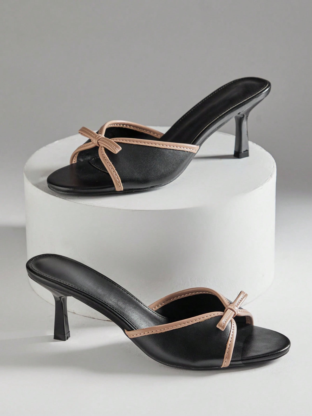 Black pointy toe kitten heel shoes for women featuring a sleek cut out mule design and glossy patent leather finish.