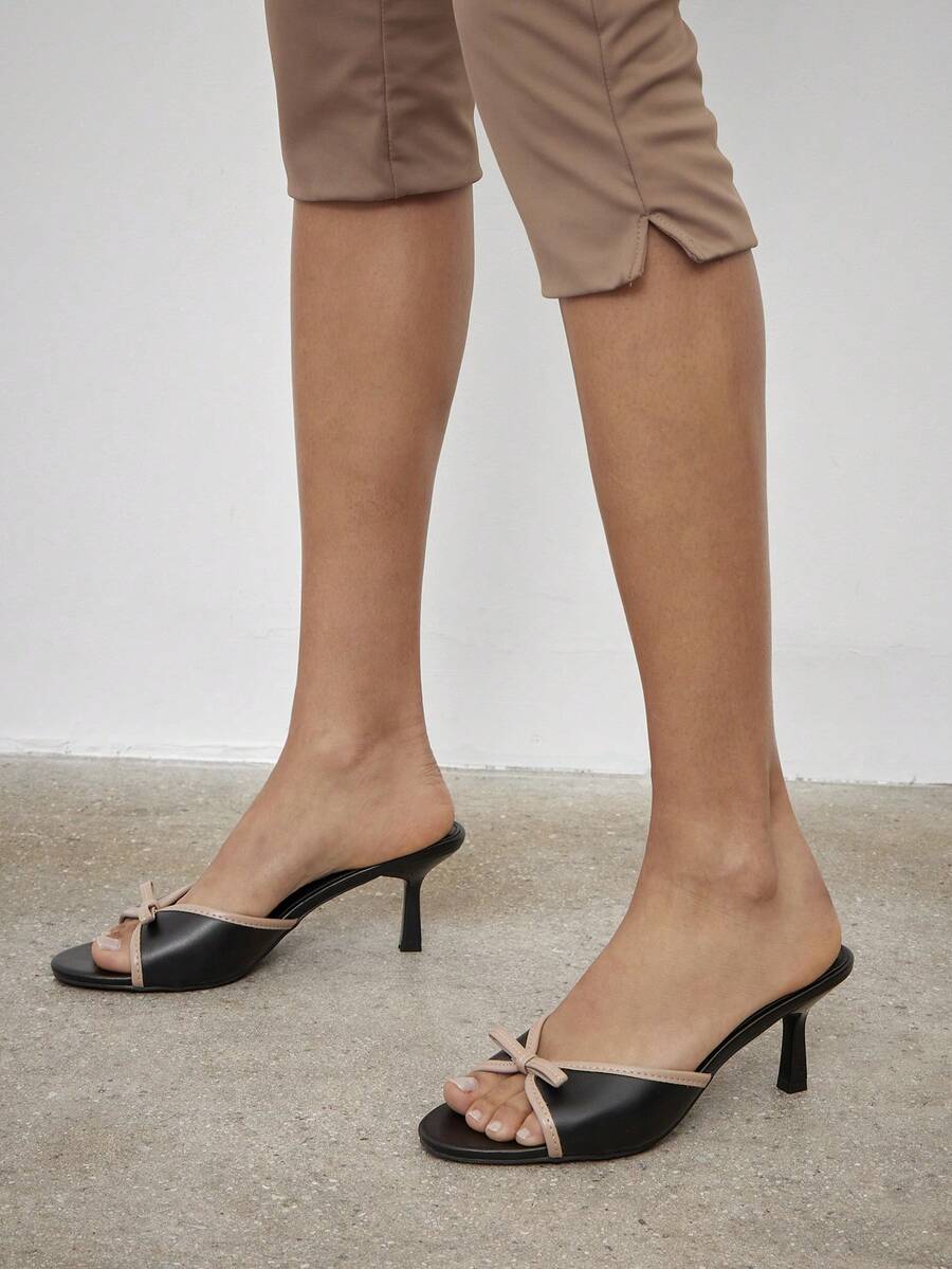 Black pointy toe kitten heel shoes for women featuring a sleek cut out mule design and glossy patent leather finish.