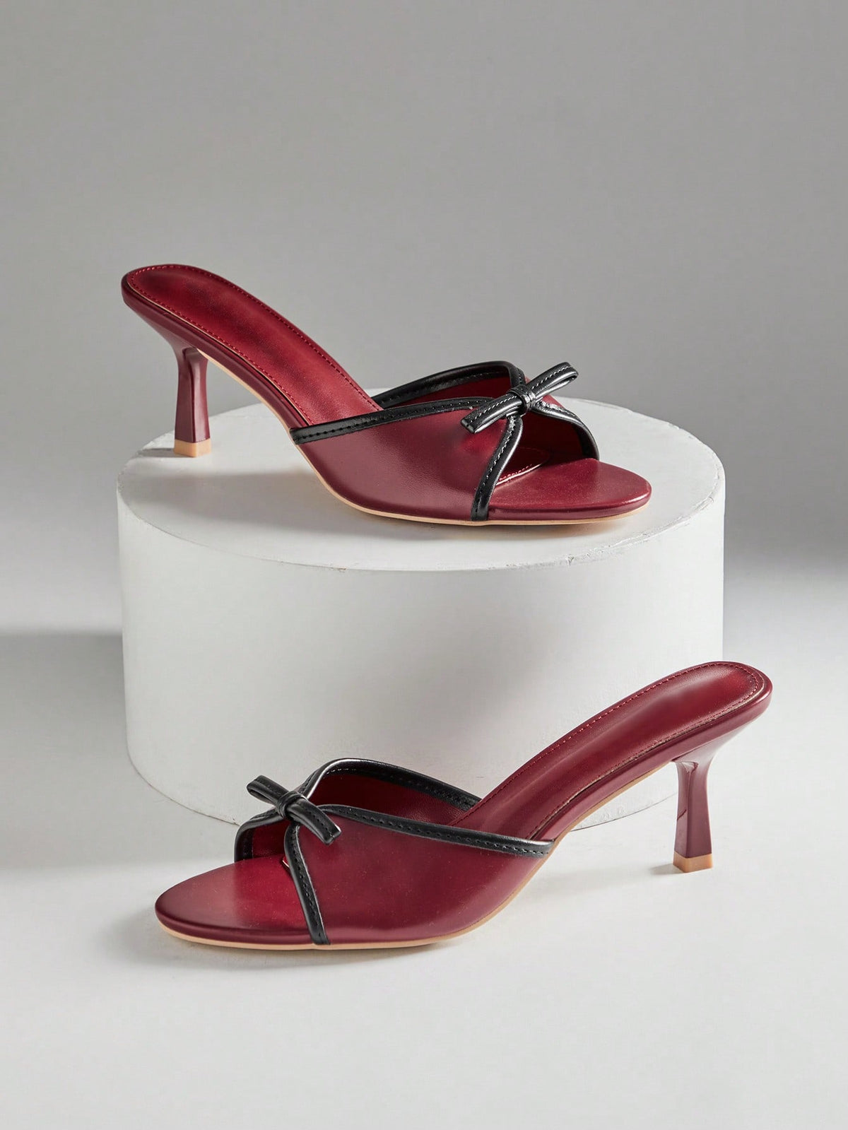 Black pointy toe kitten heel shoes for women featuring a sleek cut out mule design and glossy patent leather finish.