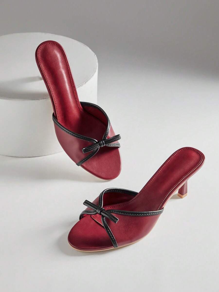 Black pointy toe kitten heel shoes for women featuring a sleek cut out mule design and glossy patent leather finish.