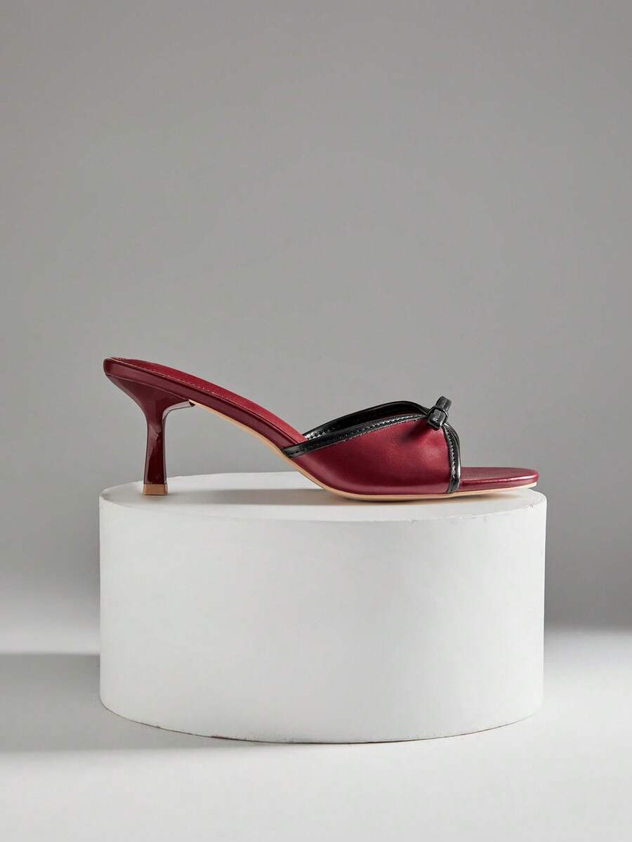 Black pointy toe kitten heel shoes for women featuring a sleek cut out mule design and glossy patent leather finish.