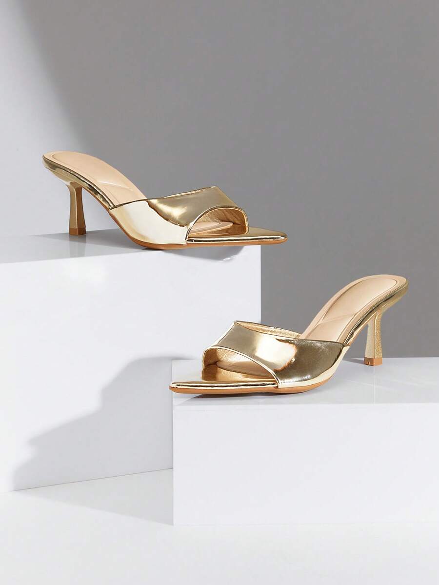 Black pointy toe kitten heel shoes for women featuring a sleek cut out mule design and glossy patent leather finish.