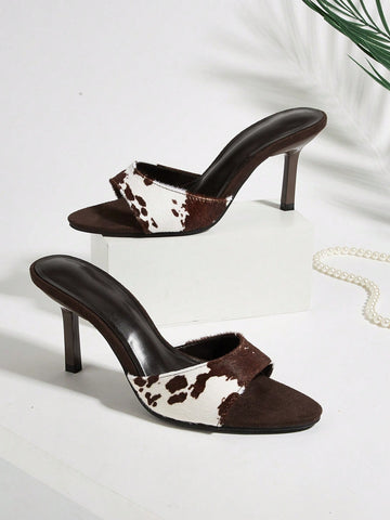 Brown cow print and polka dot stiletto high heel sandals with an open peep toe, satin upper, and buckle accent.