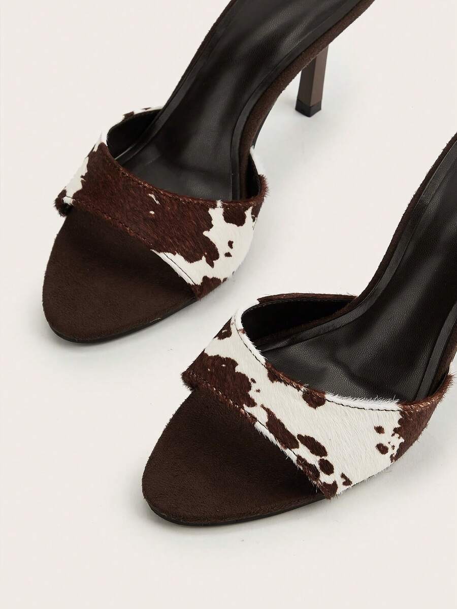 Brown cow print and polka dot stiletto high heel sandals with an open peep toe, satin upper, and buckle accent.