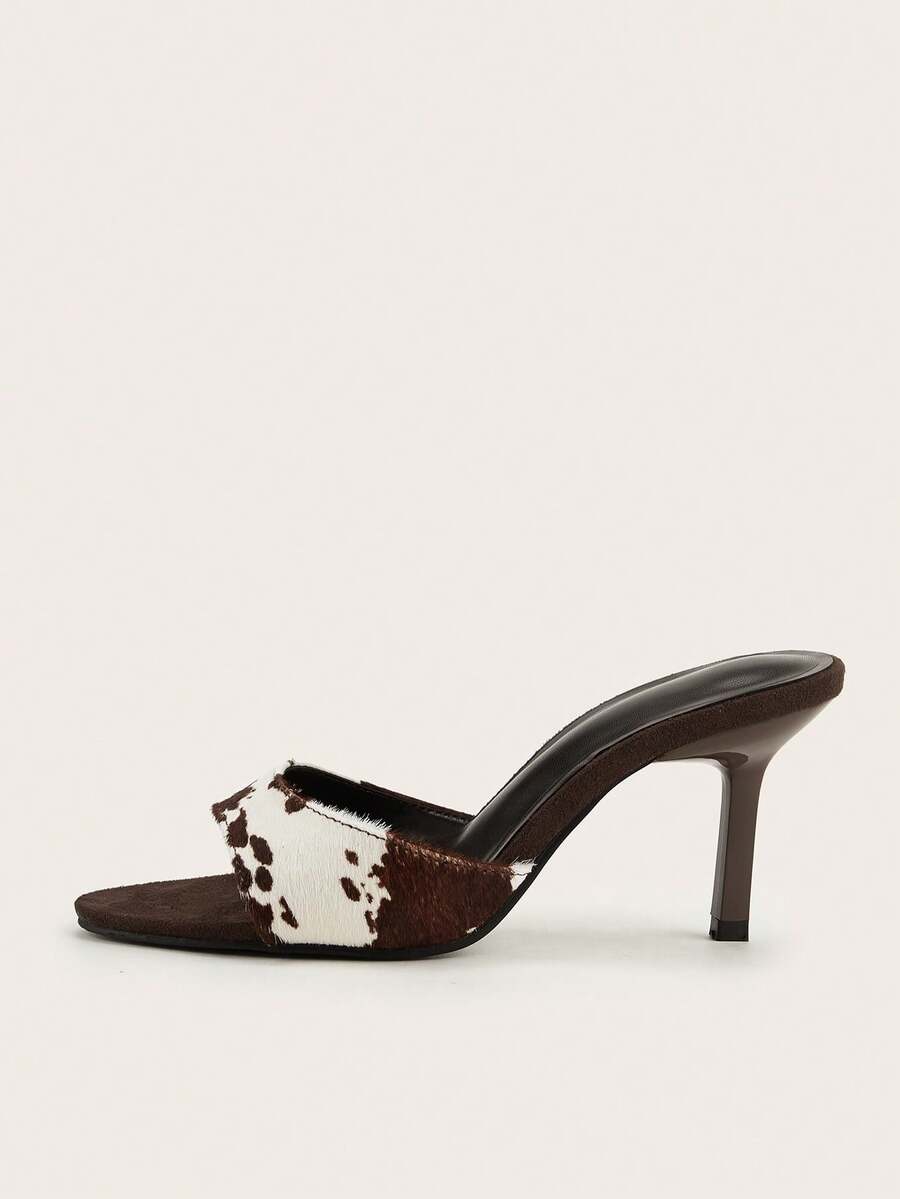 Brown cow print and polka dot stiletto high heel sandals with an open peep toe, satin upper, and buckle accent.