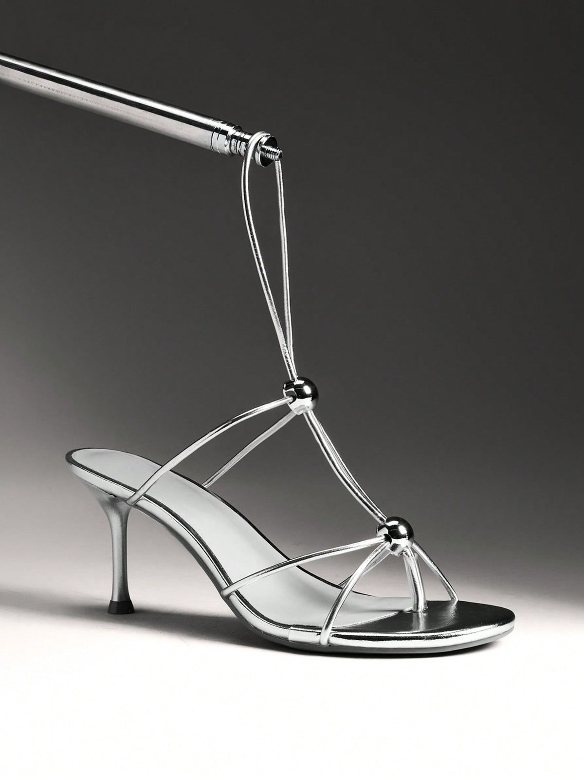 Women's strappy stiletto heel sandals crafted in vegan PU leather featuring open toe design and metallic bead accents.