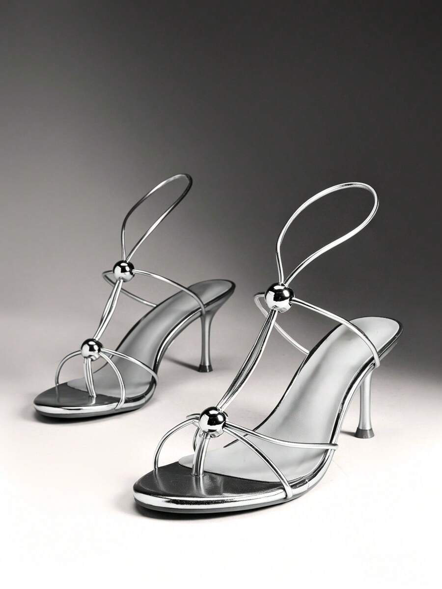 Women's strappy stiletto heel sandals crafted in vegan PU leather featuring open toe design and metallic bead accents.