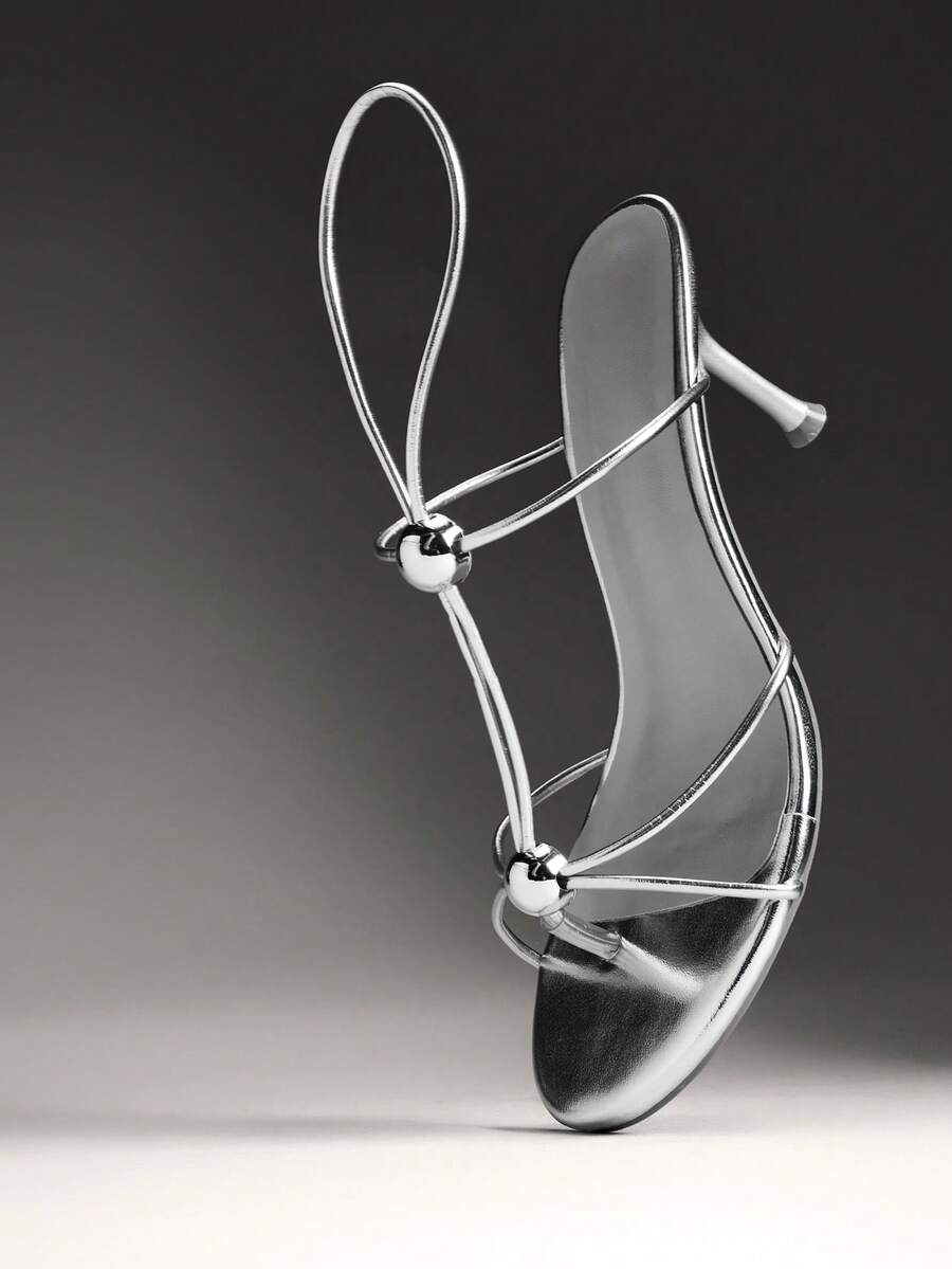 Women's strappy stiletto heel sandals crafted in vegan PU leather featuring open toe design and metallic bead accents.