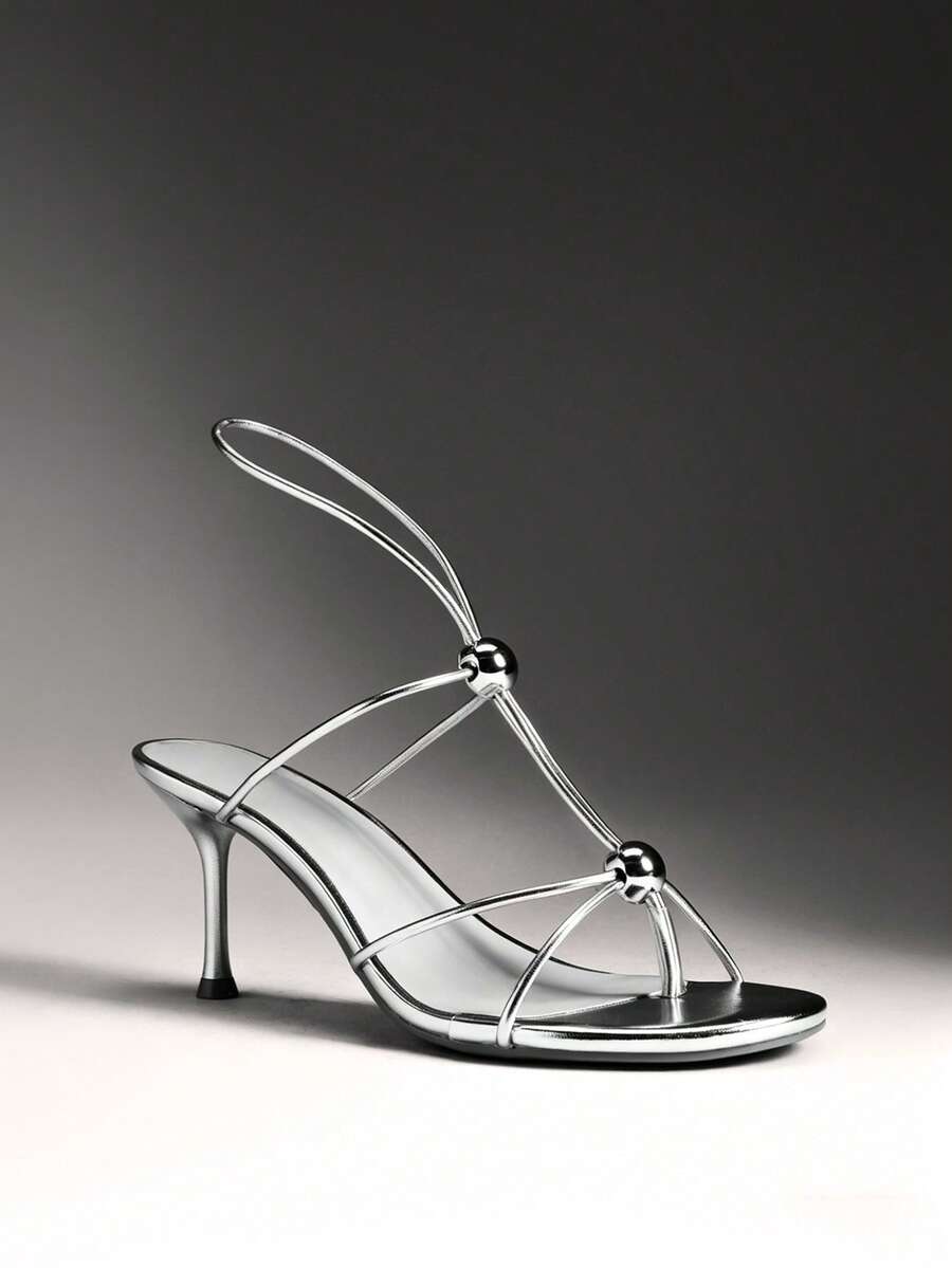 Women's strappy stiletto heel sandals crafted in vegan PU leather featuring open toe design and metallic bead accents.