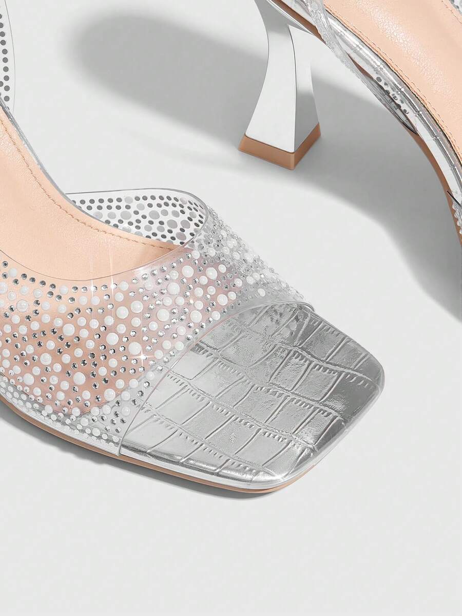 Women's square toe heeled sandals with clear straps, sparkling rhinestone embellishments, and a high pyramid heel.