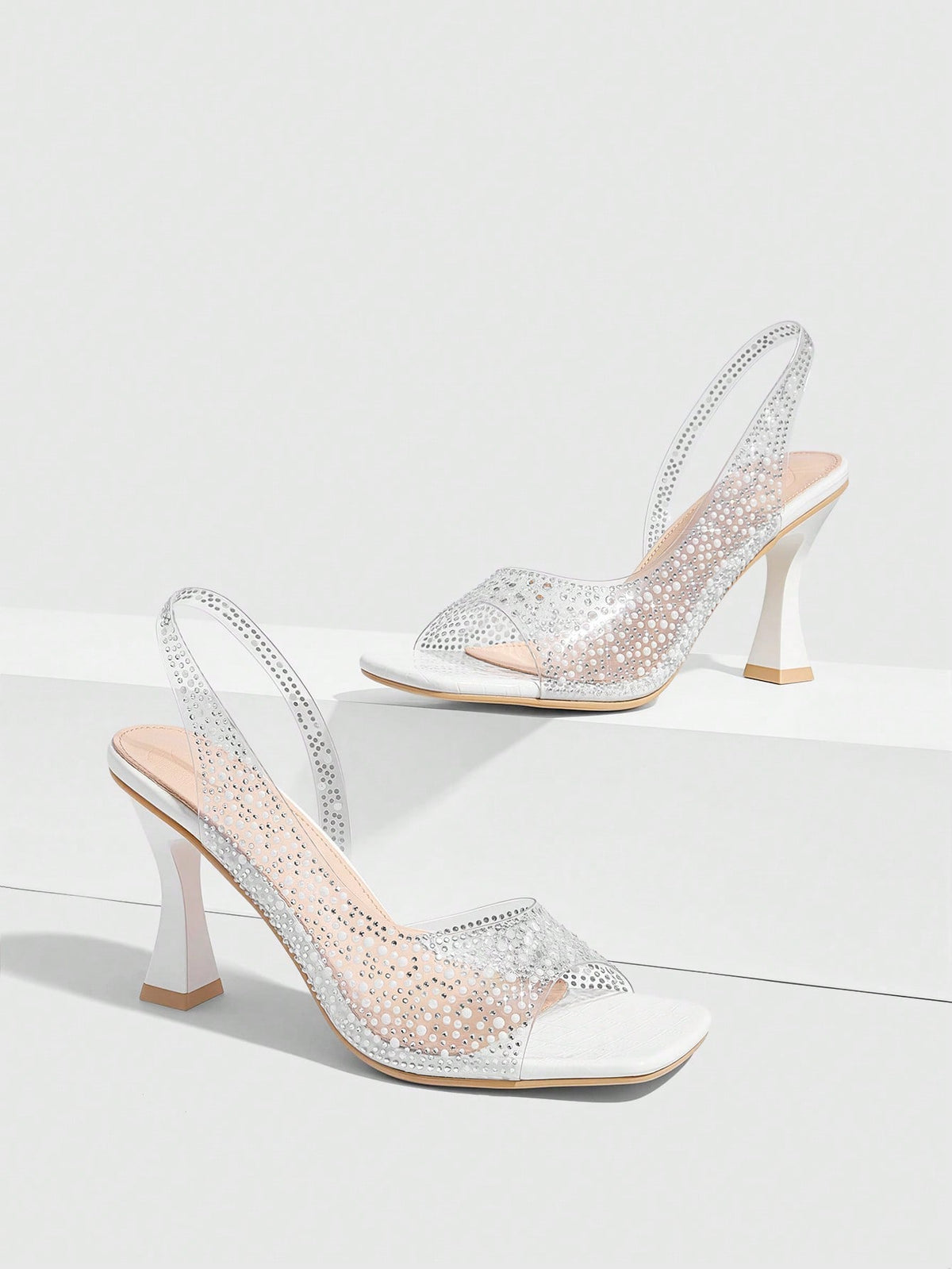 Women's square toe heeled sandals with clear straps, sparkling rhinestone embellishments, and a high pyramid heel.