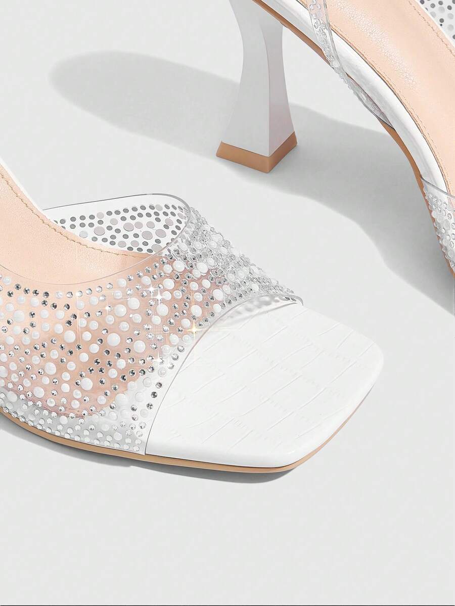 Women's square toe heeled sandals with clear straps, sparkling rhinestone embellishments, and a high pyramid heel.
