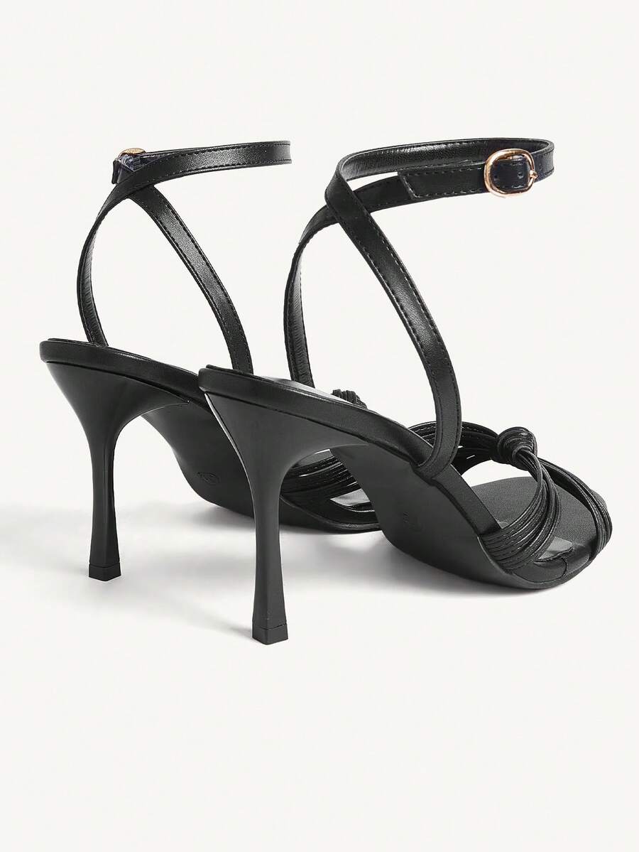 Women's champagne stiletto high heel sandals featuring knotted cross-over straps, open round toe, and adjustable ankle buckle strap.