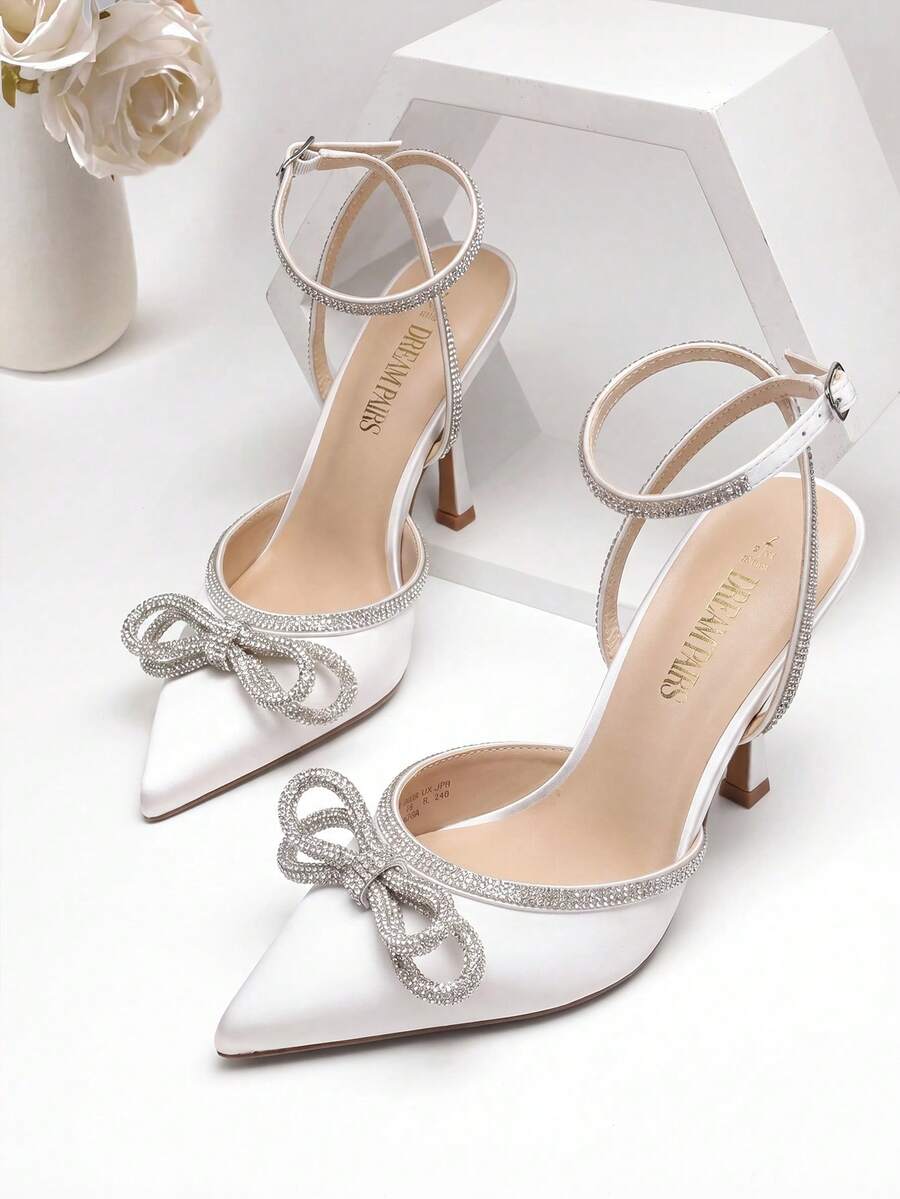 Women's rhinestone ankle strap high heels with pointed closed toe, strappy bow details, and stiletto heel for wedding and prom wear.