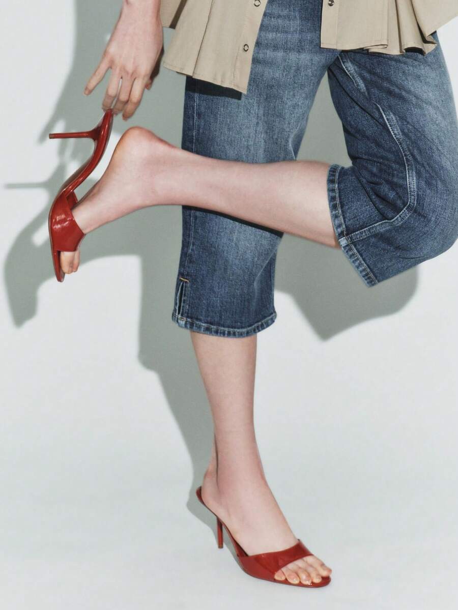 Pair of women's open toe patent leather mule shoes with sleek stiletto heels and cut-out styling