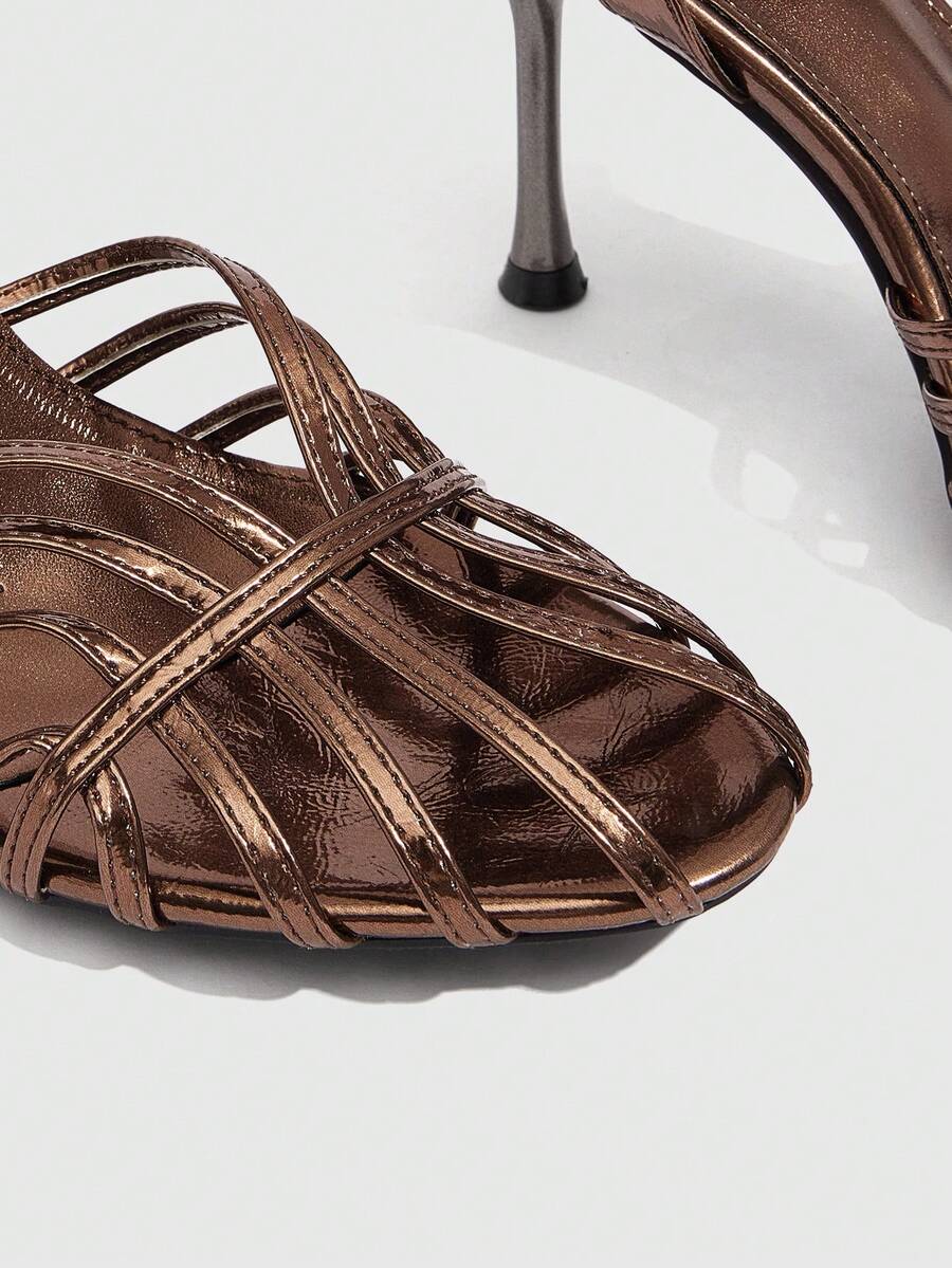 Women's glossy silver open-toed sandals with thin pyramid heel and strappy ribbon details.