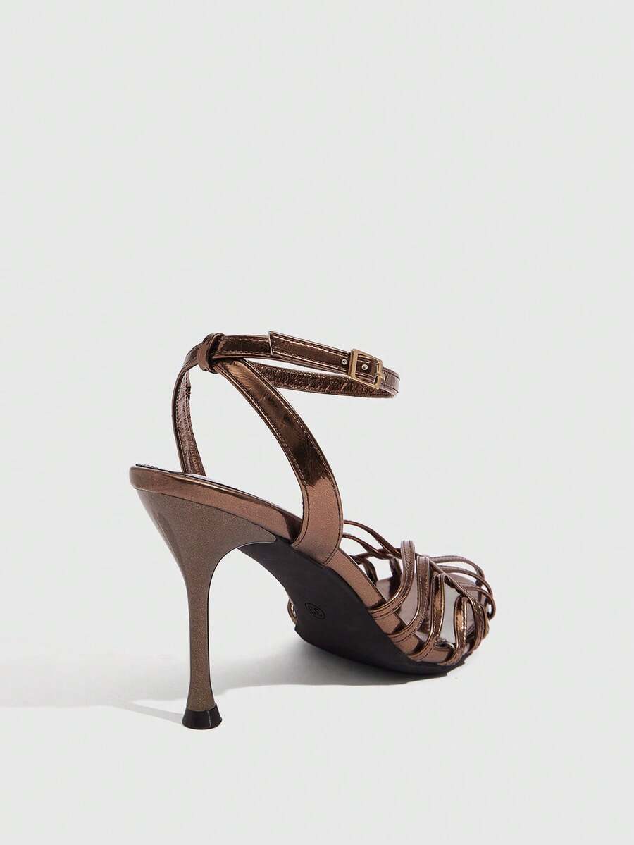Women's glossy silver open-toed sandals with thin pyramid heel and strappy ribbon details.