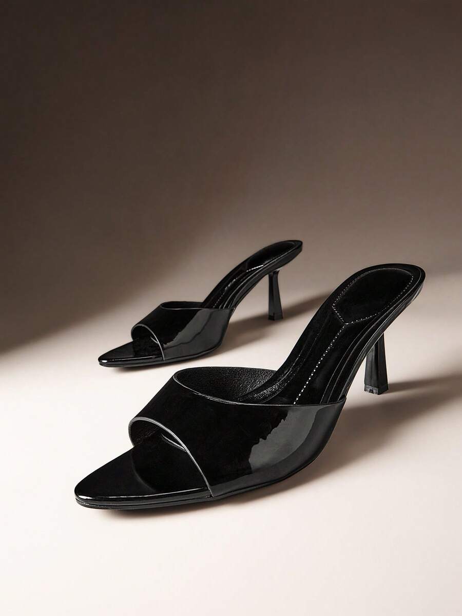 Pair of women's minimalist black pointy toe stiletto heel sandals with slingback straps.