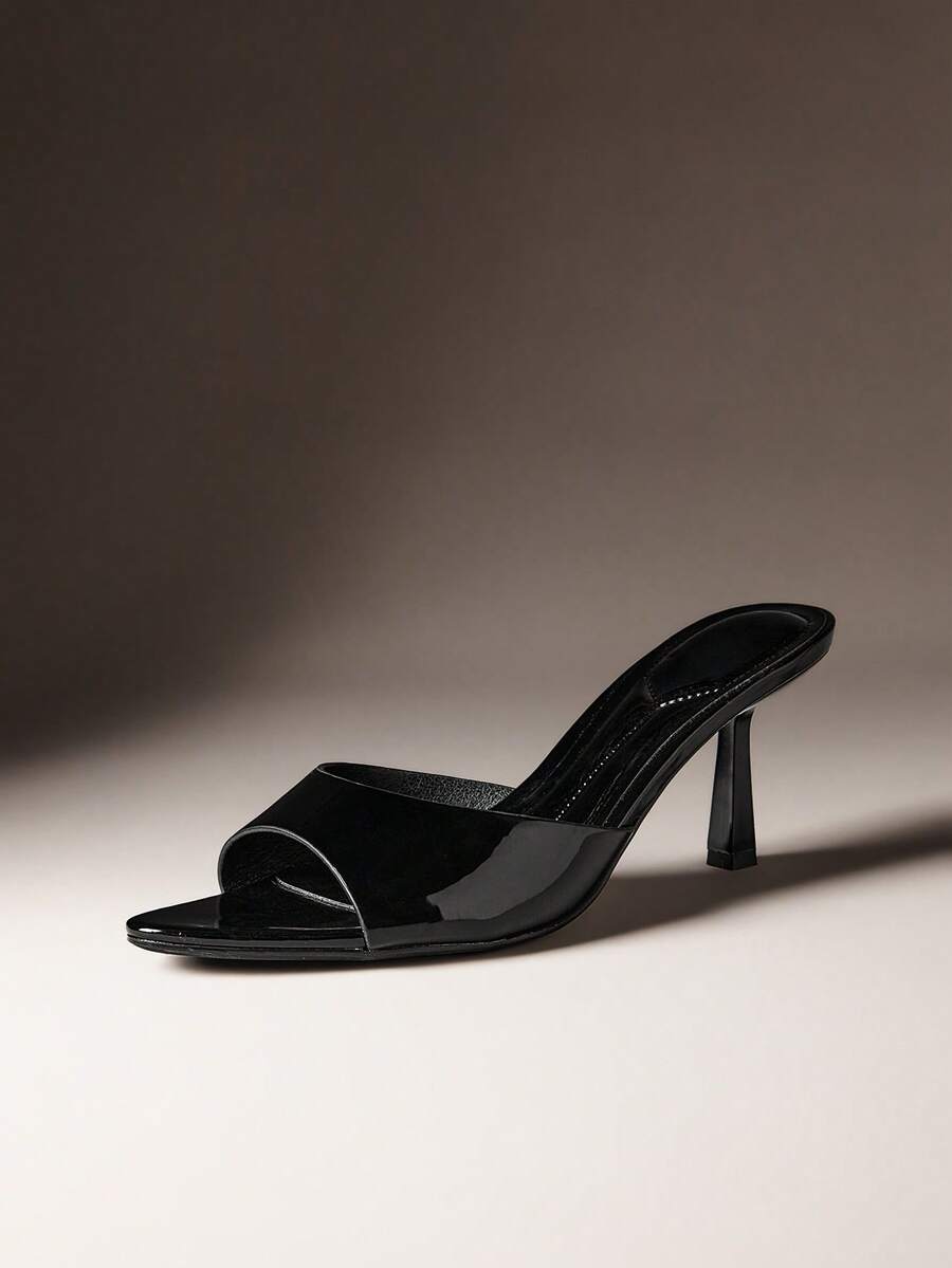 Pair of women's minimalist black pointy toe stiletto heel sandals with slingback straps.