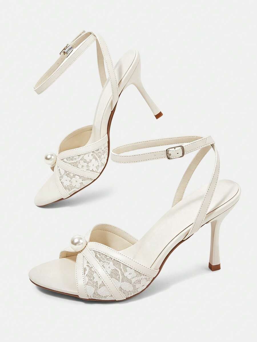 Beige high heel sandals with delicate lace overlay, pearl embellishments, stiletto heel, and adjustable ankle strap for bride and wedding party wear.