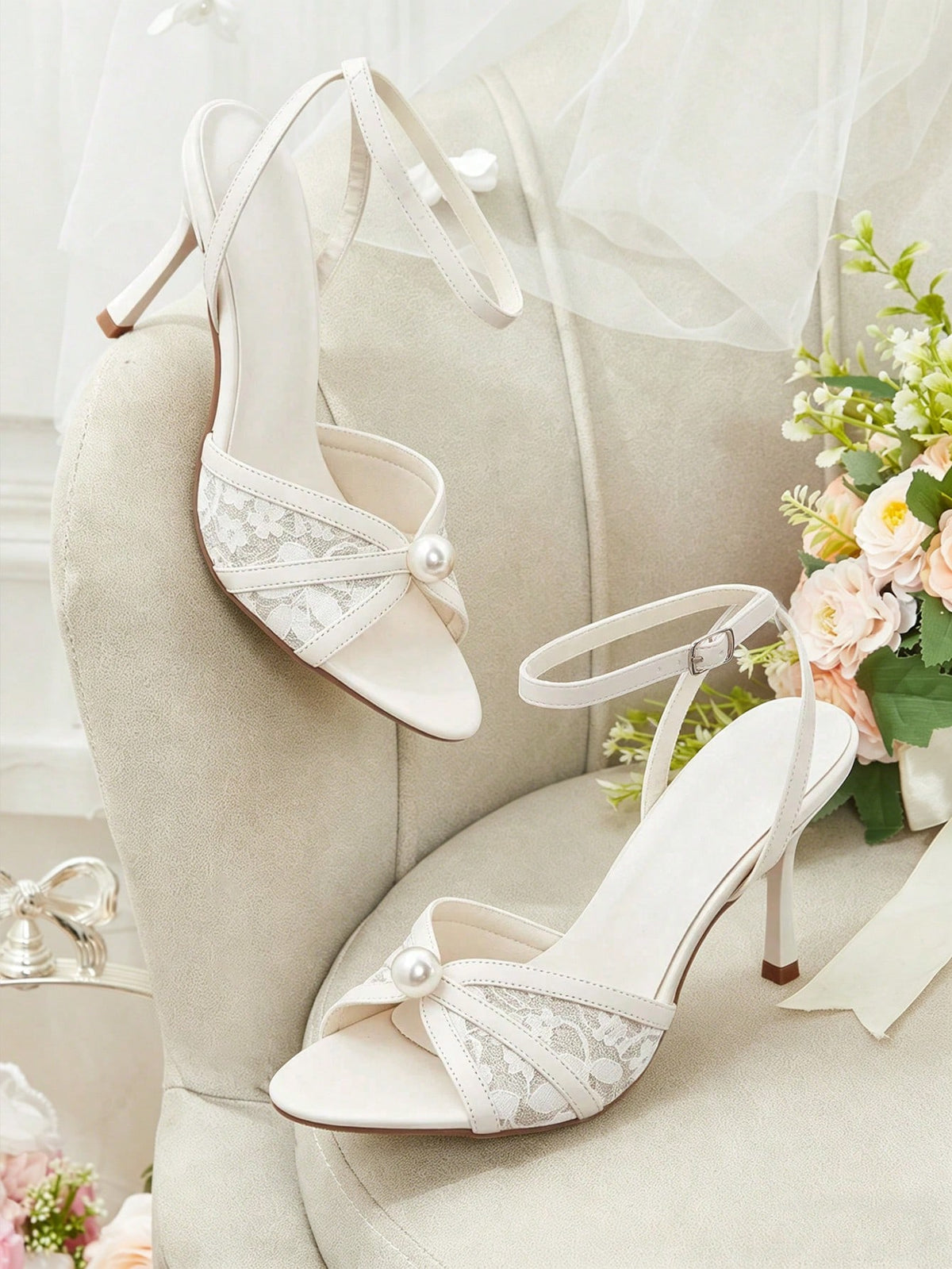 Beige high heel sandals with delicate lace overlay, pearl embellishments, stiletto heel, and adjustable ankle strap for bride and wedding party wear.