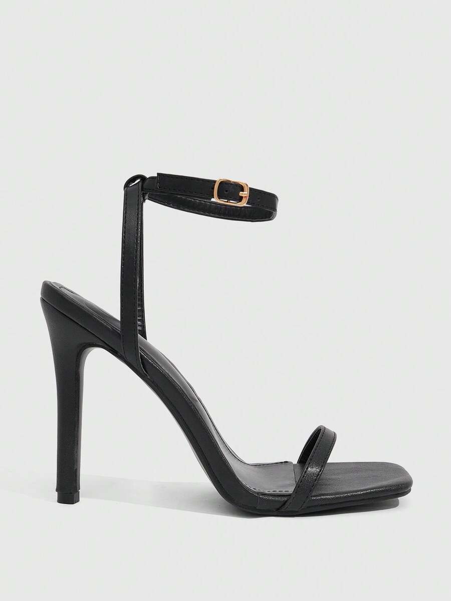 Women's minimalist black heeled sandals featuring an open toe, stiletto high heel, and adjustable ankle strap buckle closure.