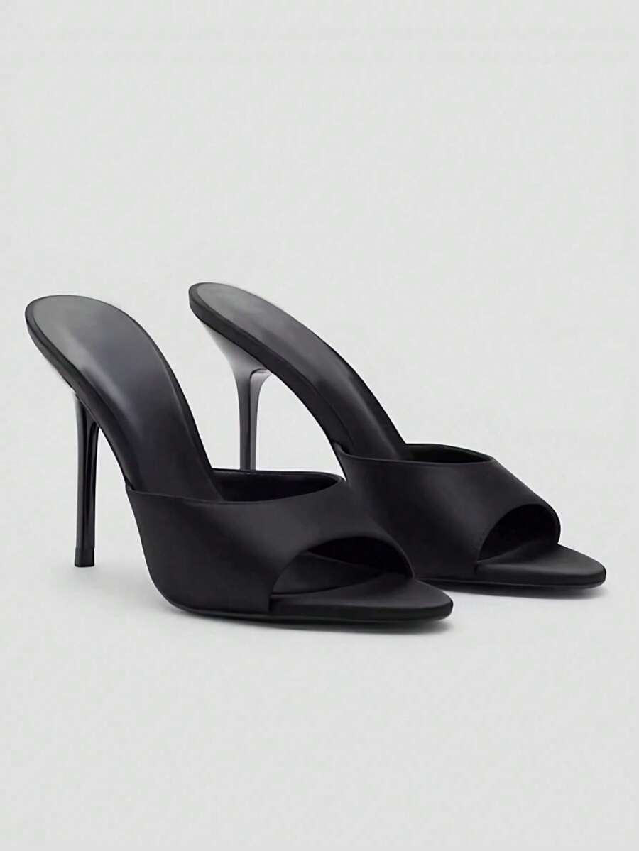 Pair of women's open toe patent leather mule shoes with sleek stiletto heels and cut-out styling