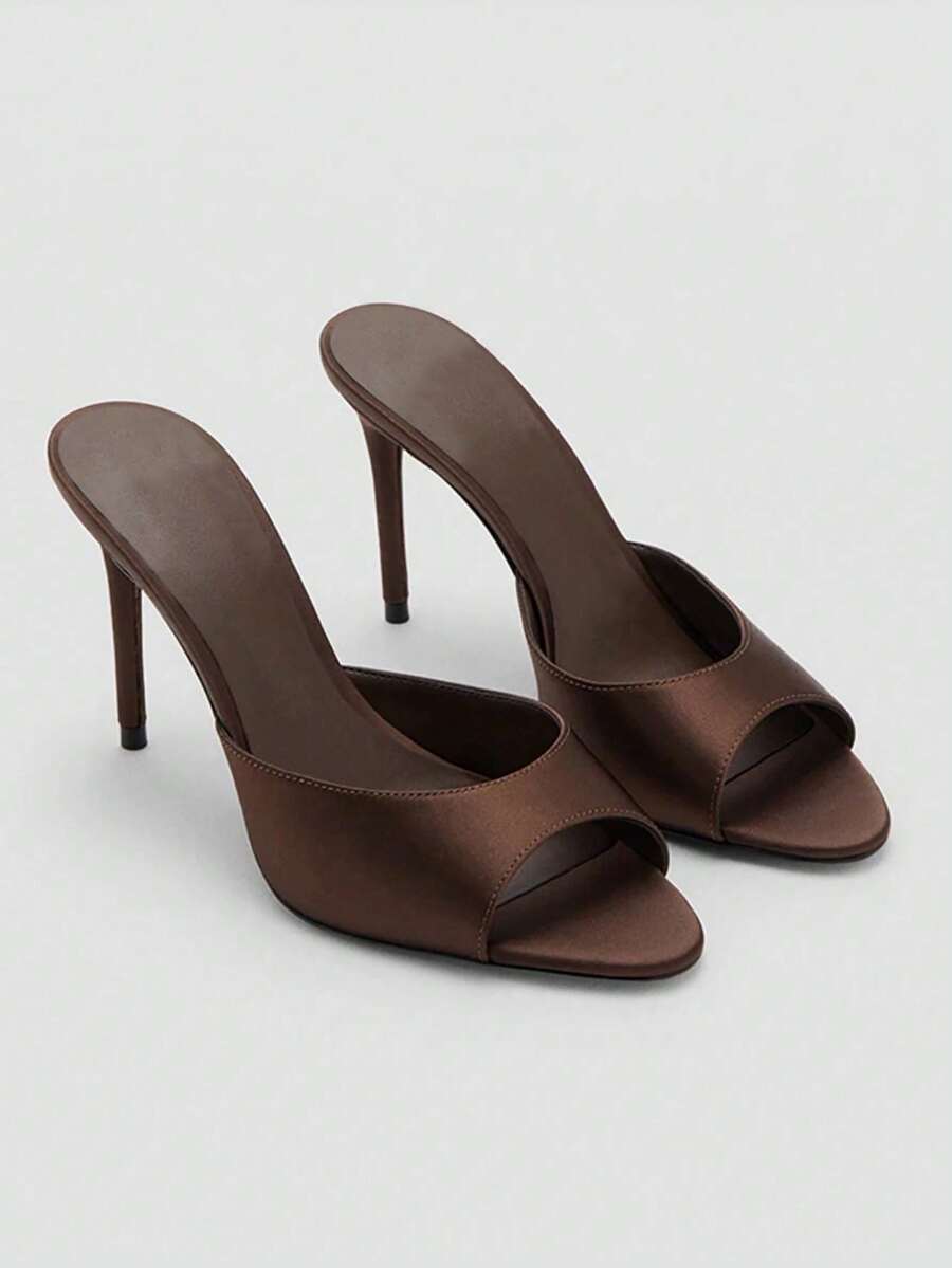 Pair of women's open toe patent leather mule shoes with sleek stiletto heels and cut-out styling