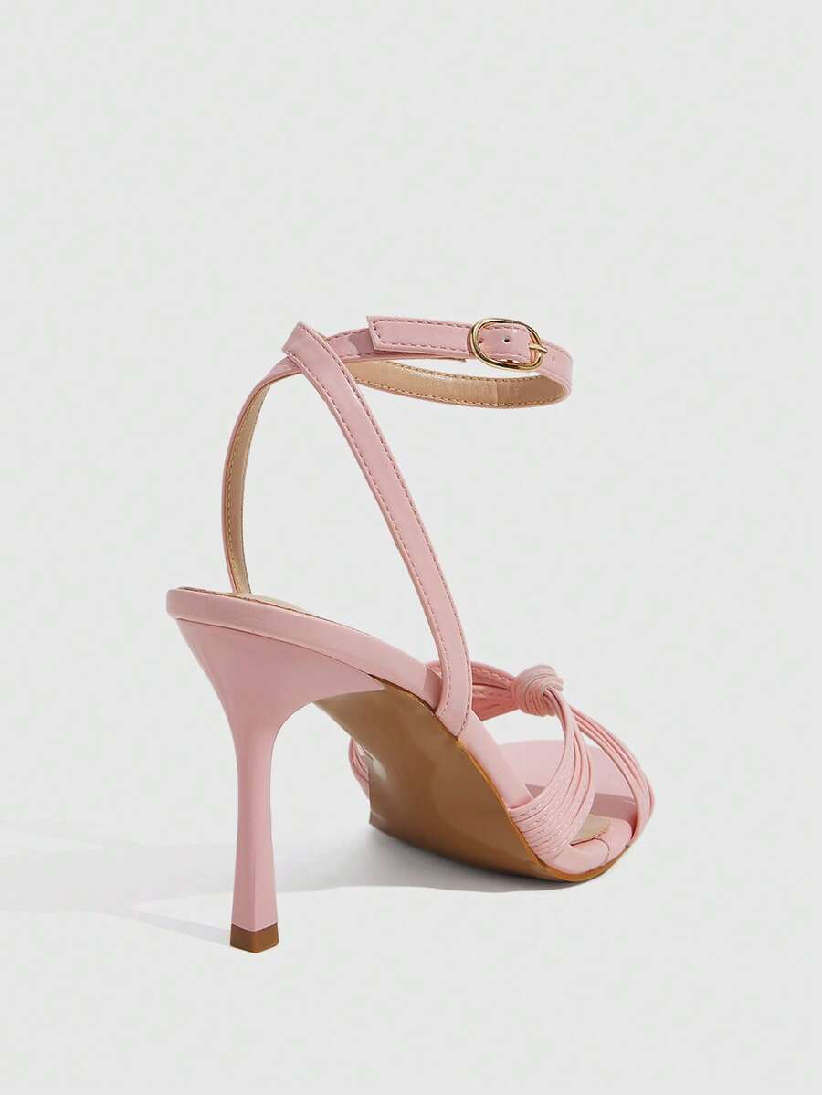 Women's champagne stiletto high heel sandals featuring knotted cross-over straps, open round toe, and adjustable ankle buckle strap.