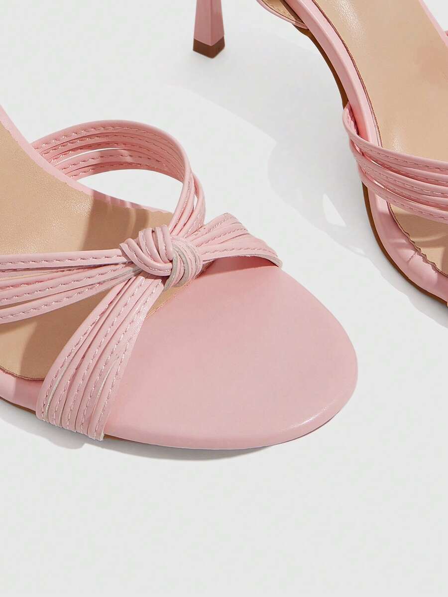 Women's champagne stiletto high heel sandals featuring knotted cross-over straps, open round toe, and adjustable ankle buckle strap.