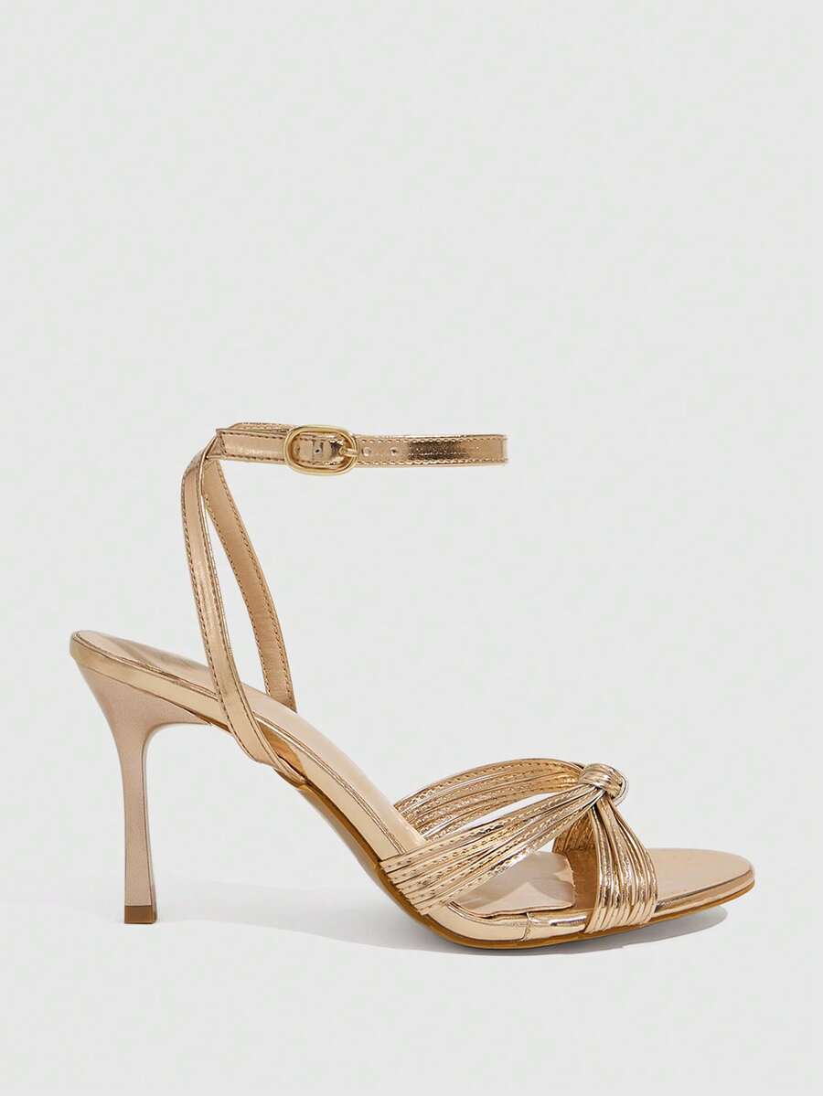 Women's champagne stiletto high heel sandals featuring knotted cross-over straps, open round toe, and adjustable ankle buckle strap.