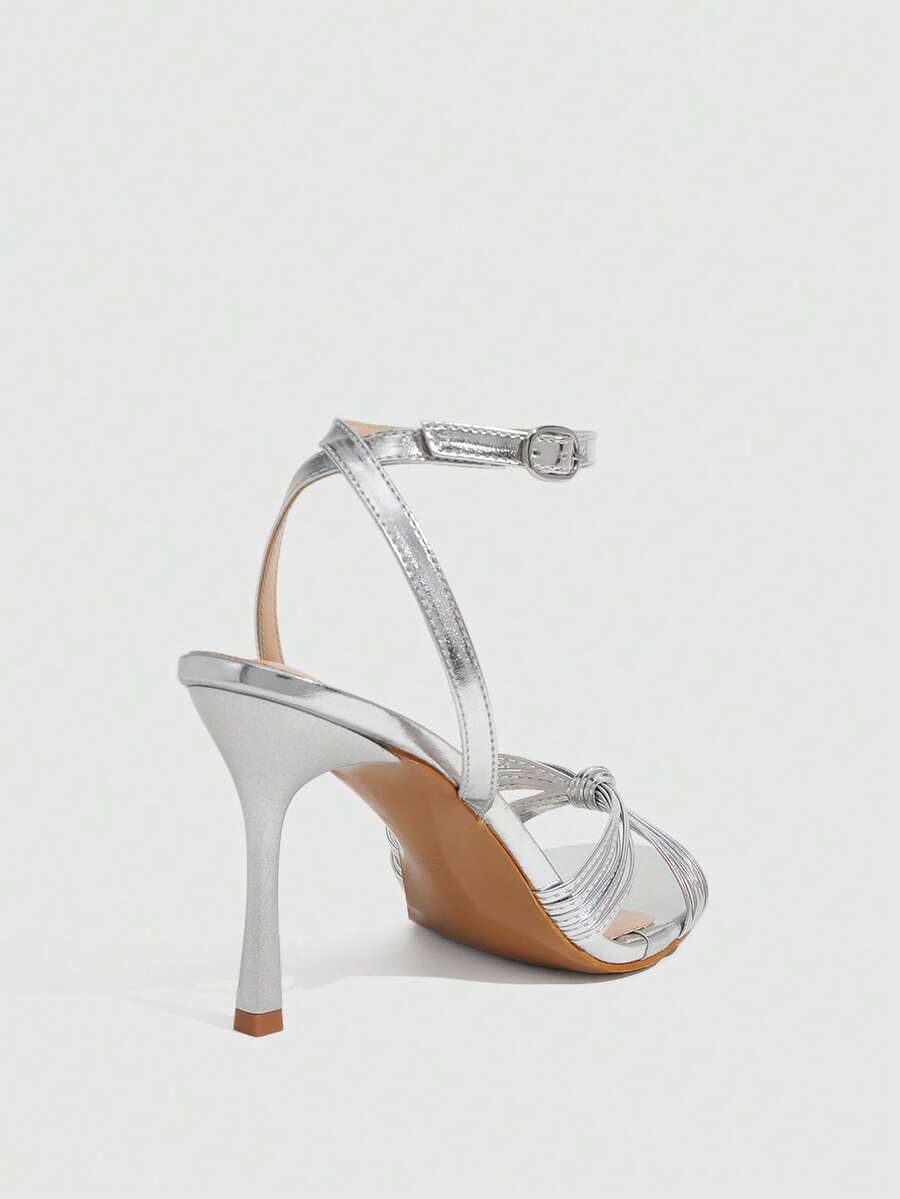 Women's champagne stiletto high heel sandals featuring knotted cross-over straps, open round toe, and adjustable ankle buckle strap.