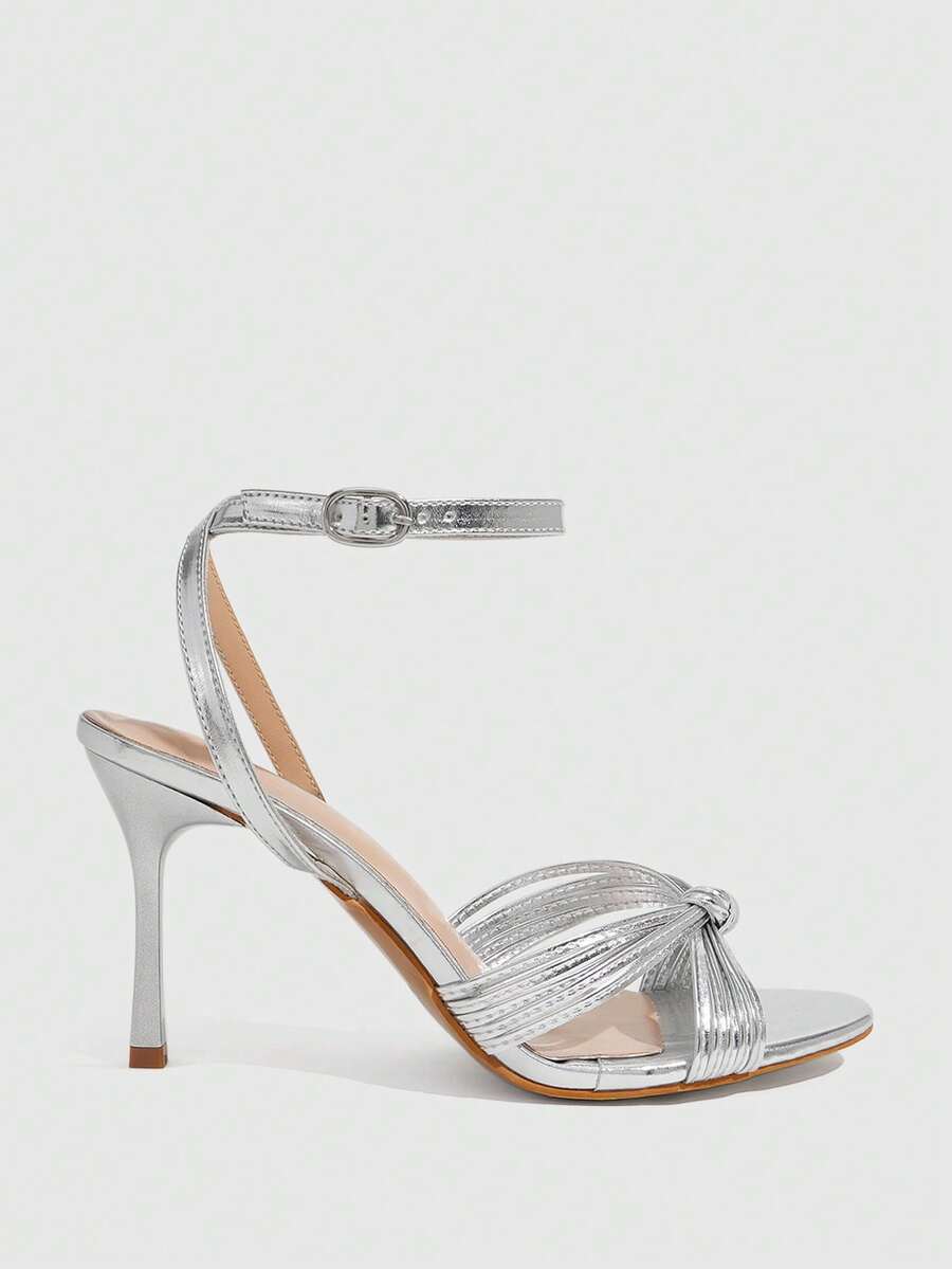 Women's champagne stiletto high heel sandals featuring knotted cross-over straps, open round toe, and adjustable ankle buckle strap.