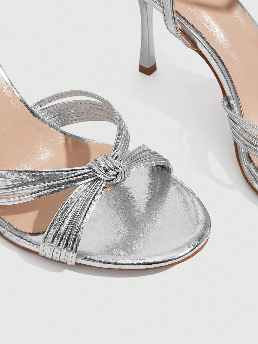 Women's champagne stiletto high heel sandals featuring knotted cross-over straps, open round toe, and adjustable ankle buckle strap.