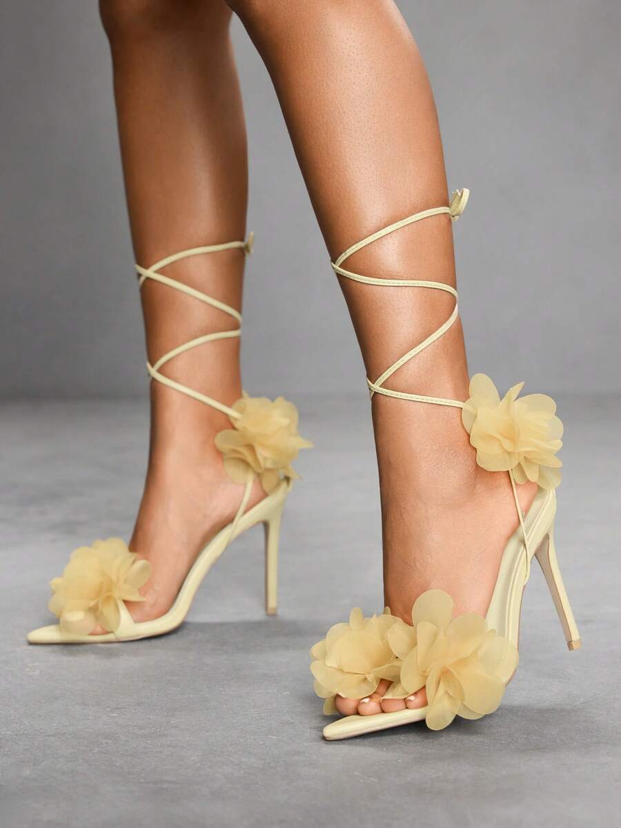 Women's open toe heeled sandals featuring 3D floral decor, satin lace-up ankle straps, and stiletto high heels.