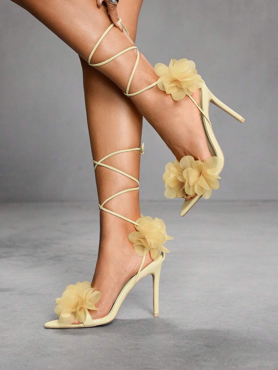 Women's open toe heeled sandals featuring 3D floral decor, satin lace-up ankle straps, and stiletto high heels.