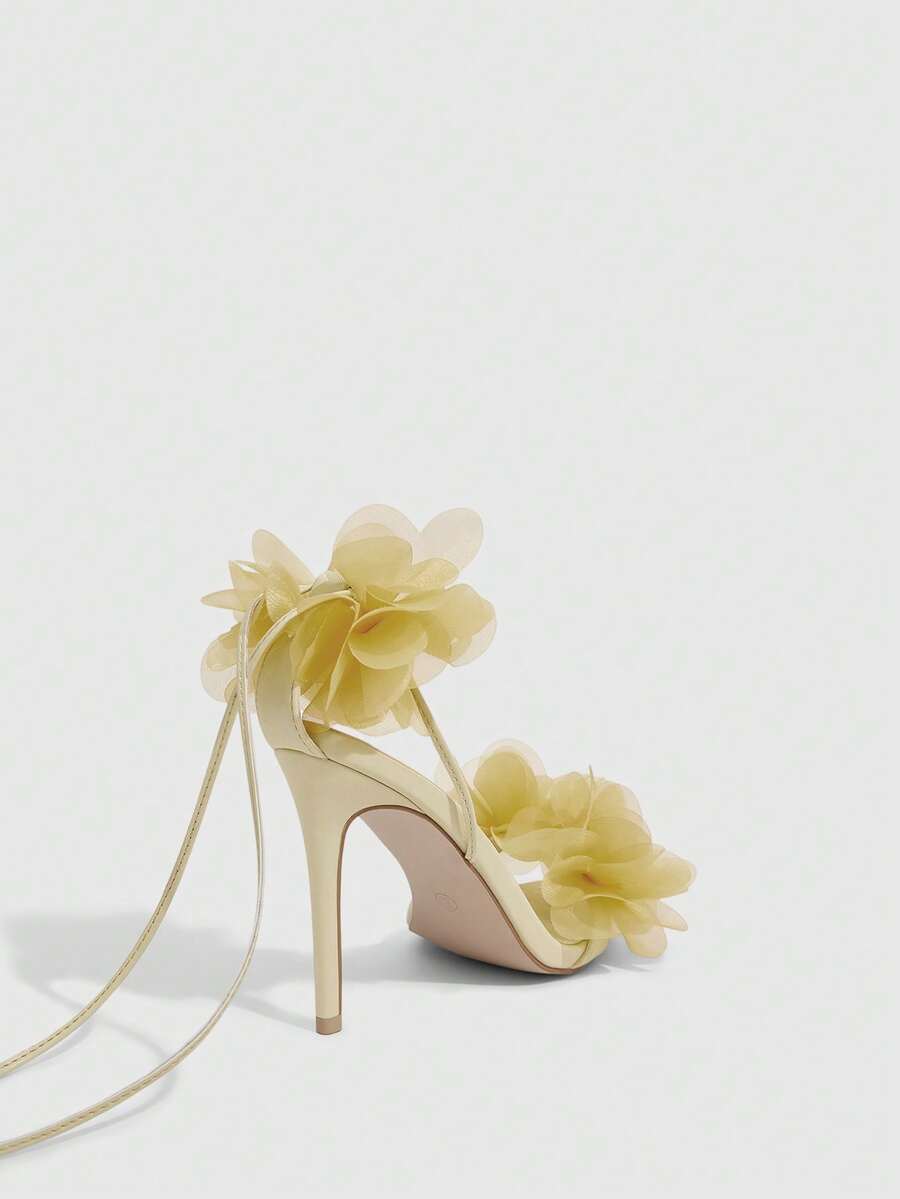 Women's open toe heeled sandals featuring 3D floral decor, satin lace-up ankle straps, and stiletto high heels.
