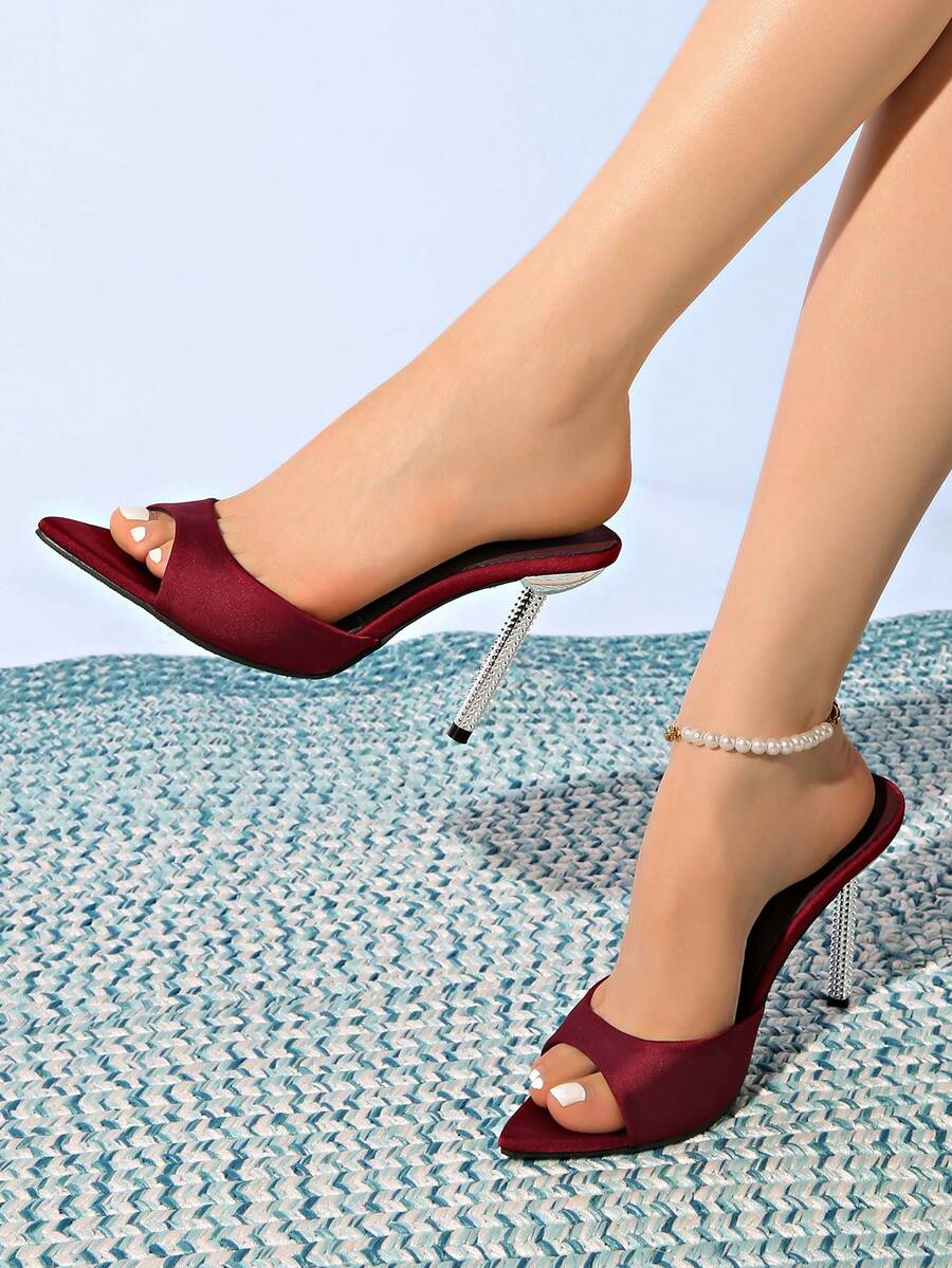 Women's black satin stiletto heeled sandals with sparkling rhinestone embellishments and a pointed peep toe design.