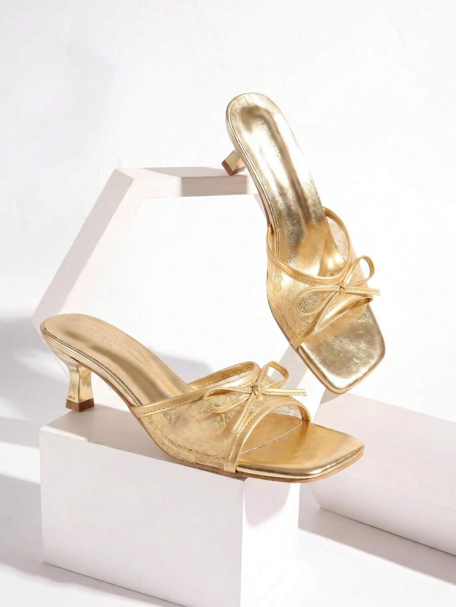 Gold kitten heel mule sandals featuring lace mesh bow detail and an open-toe slip-on design for women.