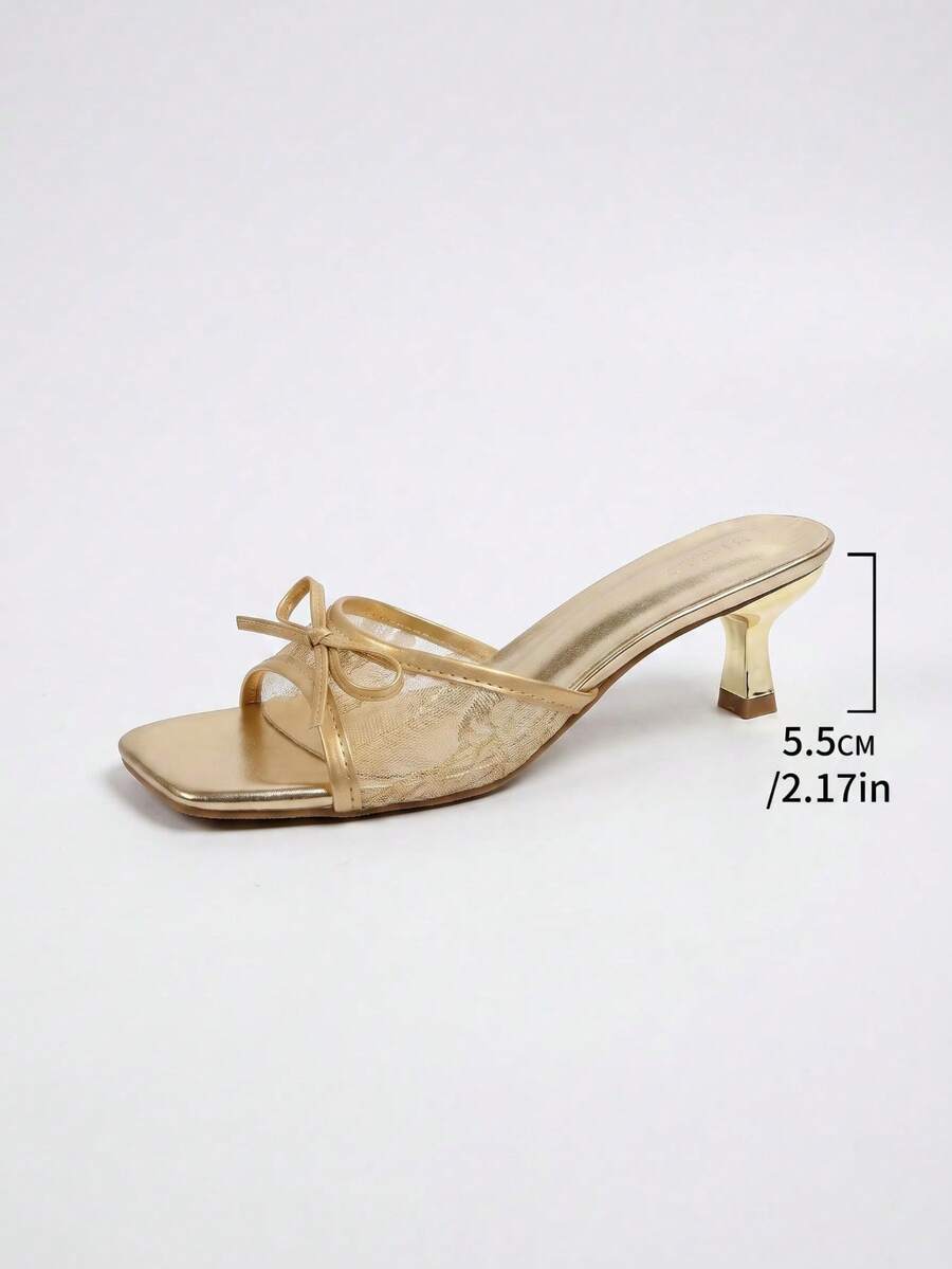 Gold kitten heel mule sandals featuring lace mesh bow detail and an open-toe slip-on design for women.