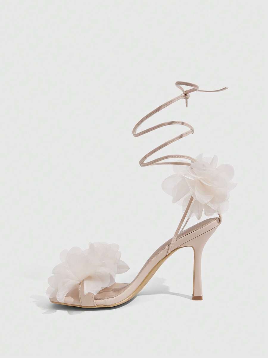Women's open toe heeled sandals featuring 3D floral decor, satin lace-up ankle straps, and stiletto high heels.