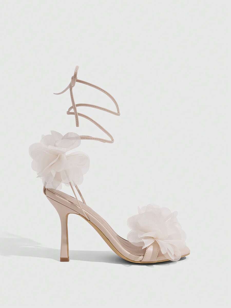 Women's open toe heeled sandals featuring 3D floral decor, satin lace-up ankle straps, and stiletto high heels.