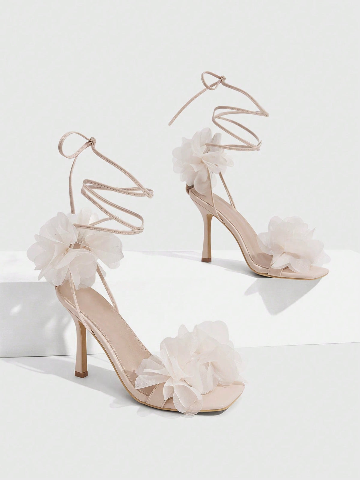 Women's open toe heeled sandals featuring 3D floral decor, satin lace-up ankle straps, and stiletto high heels.