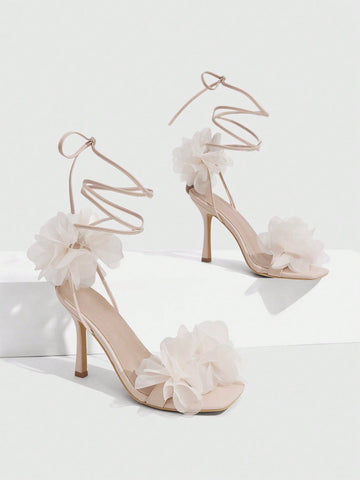 Women's open toe heeled sandals featuring 3D floral decor, satin lace-up ankle straps, and stiletto high heels.