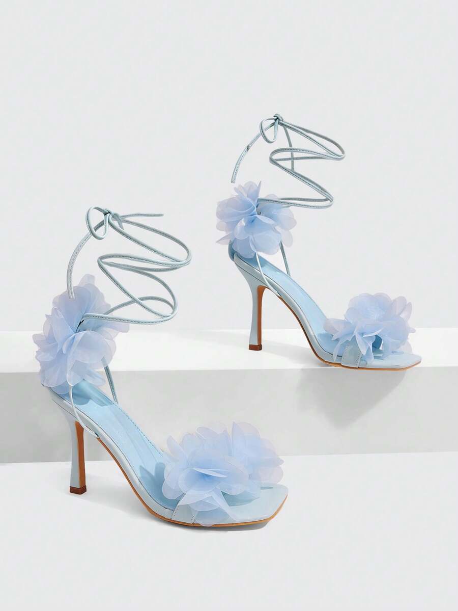 Women's open toe heeled sandals featuring 3D floral decor, satin lace-up ankle straps, and stiletto high heels.
