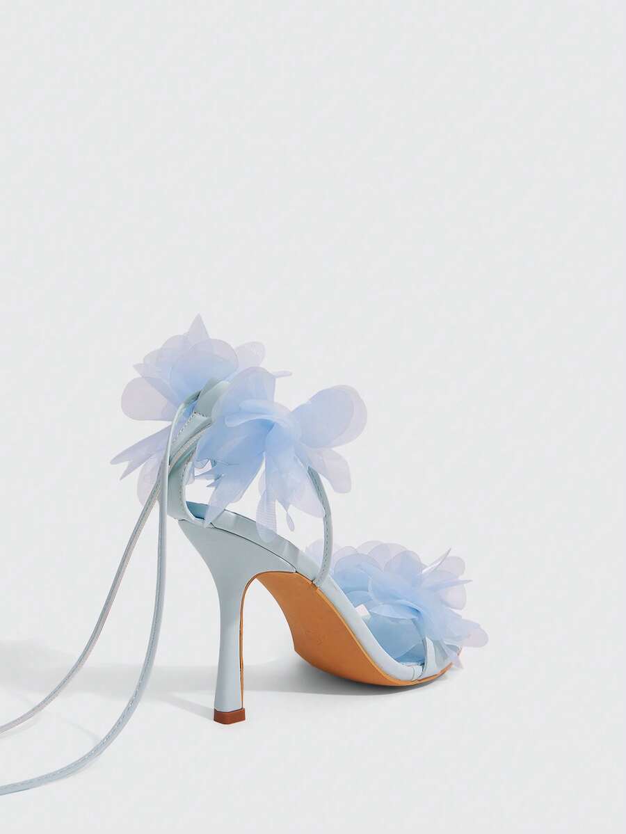 Women's open toe heeled sandals featuring 3D floral decor, satin lace-up ankle straps, and stiletto high heels.
