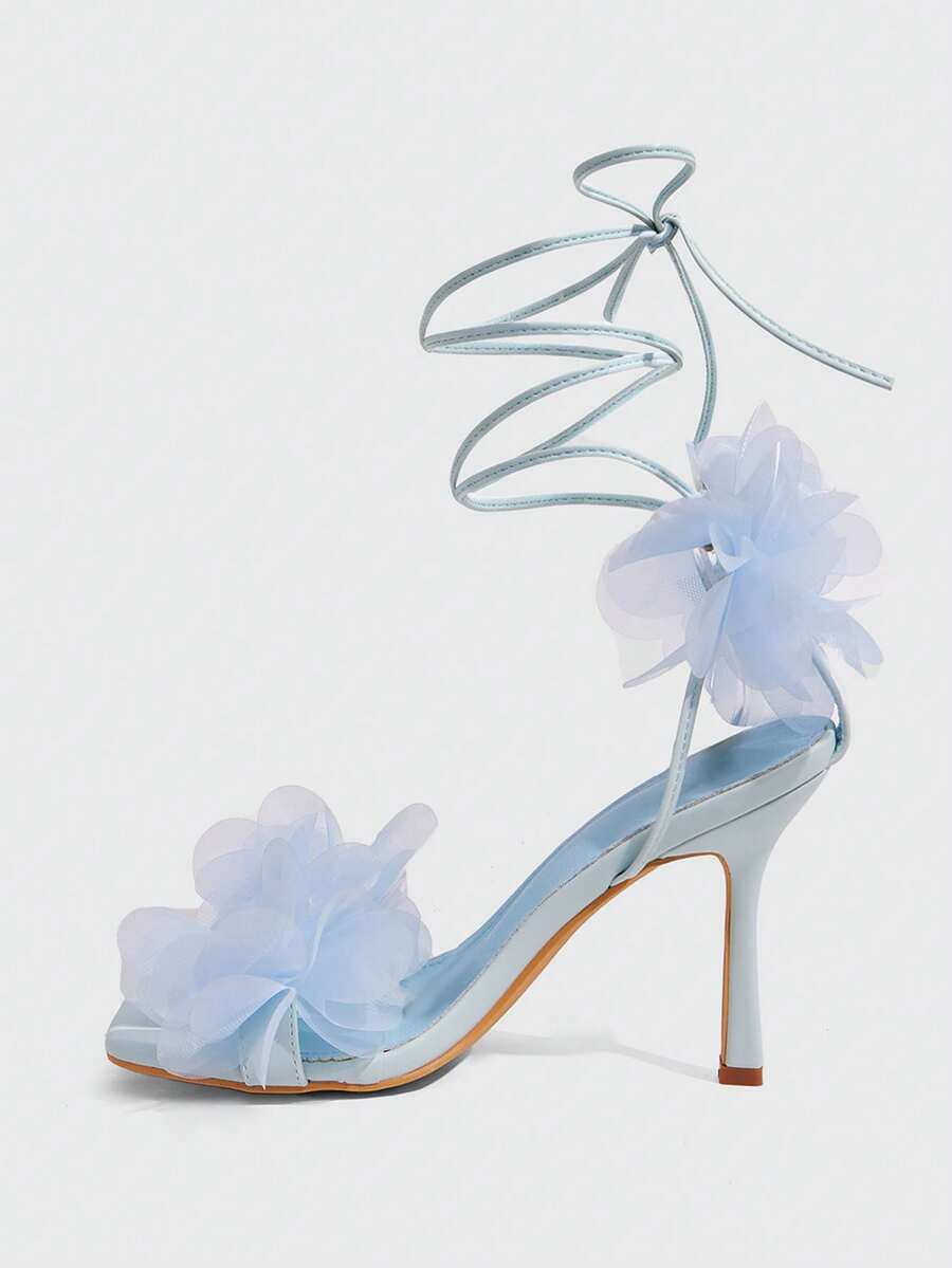 Women's open toe heeled sandals featuring 3D floral decor, satin lace-up ankle straps, and stiletto high heels.